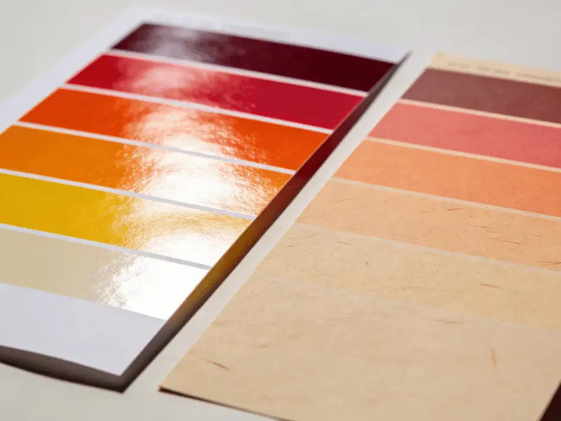 Same CMYK color swatches printed on coated glossy paper (left, vivid and sharp) versus uncoated paper (right, softer and warmer), showing how paper stock affects printed color appearance Same CMYK color swatches printed on coated glossy paper (left, vivid and sharp) versus uncoated paper (right, softer and warmer), showing how paper stock affects printed color appearance
